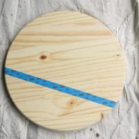 Start by taping off sections of the wood stand to paint a pattern.