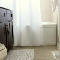 The neutral tile in this bathroom pairs well with the wood cabinets.