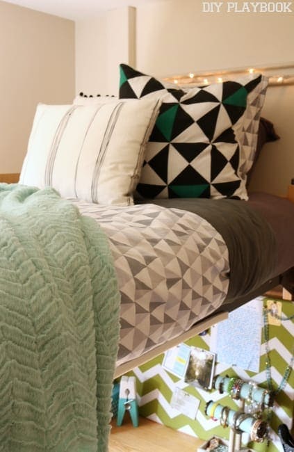 The blanket and pillows add color to the dorm room.