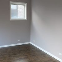 Master bedroom with elegant grey walls and beautiful stained floors.