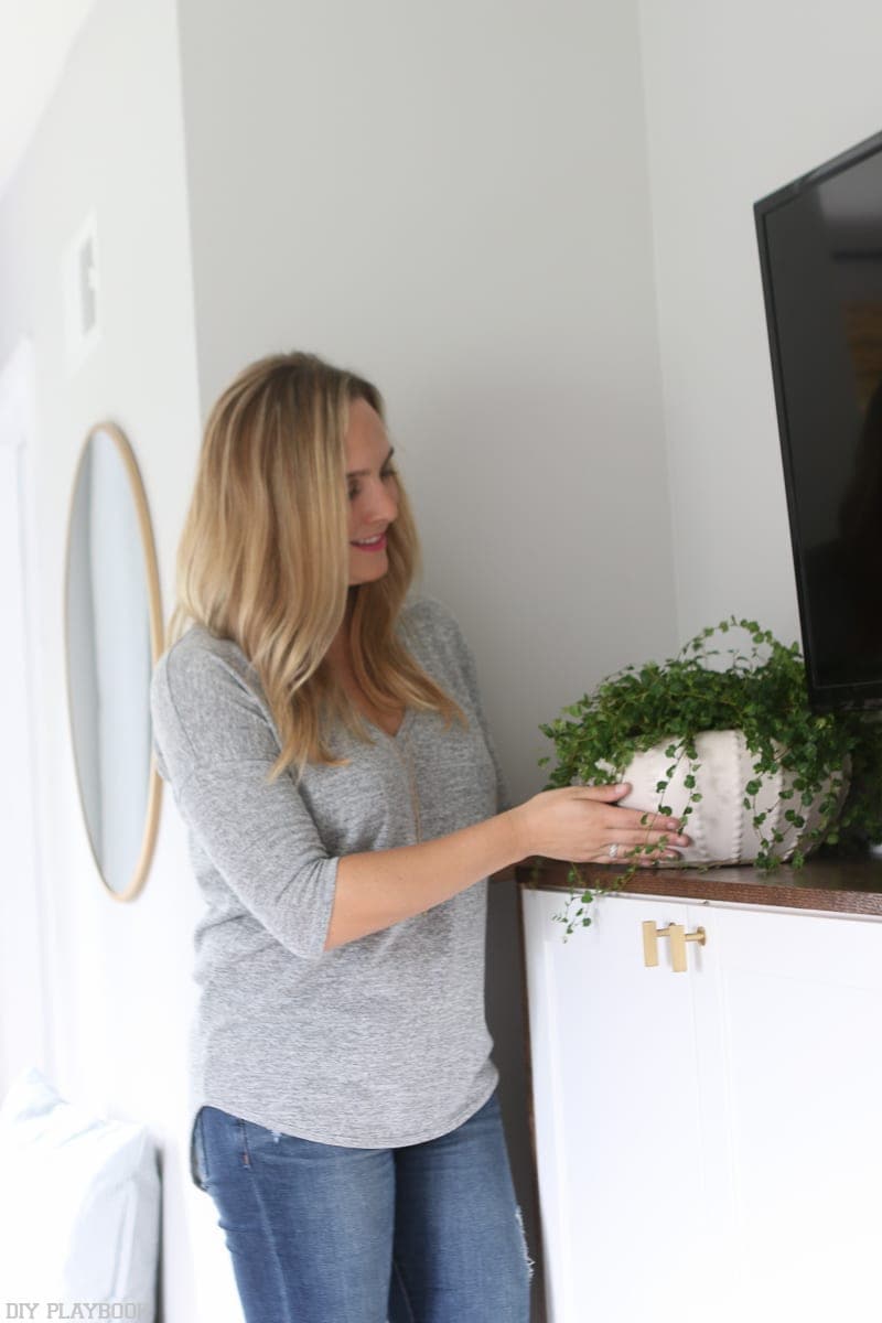 A woman adding a plant to a TV console