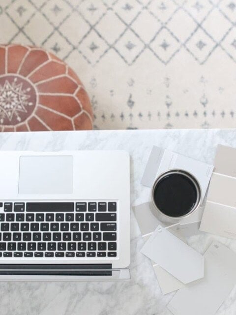 Office workspace with laptop, coffee mug, and paint sample cards.