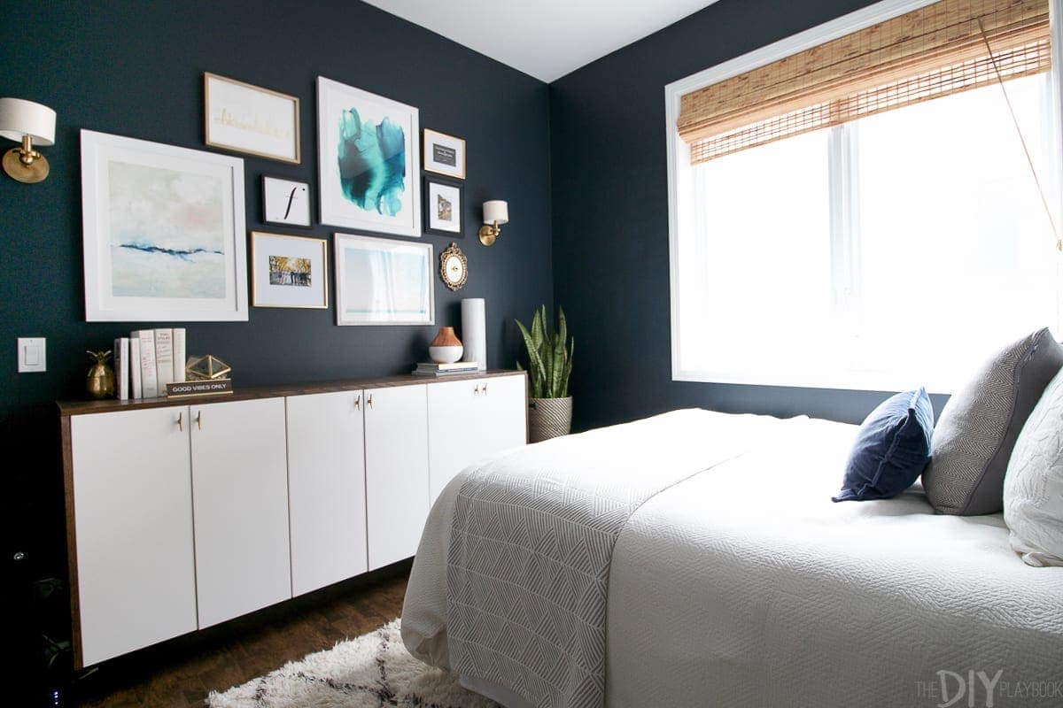 The guest bedroom has undergone a lot of changes, including navy paint on the walls! And we added a faux-denza, a gallery wall and wall sconces. 