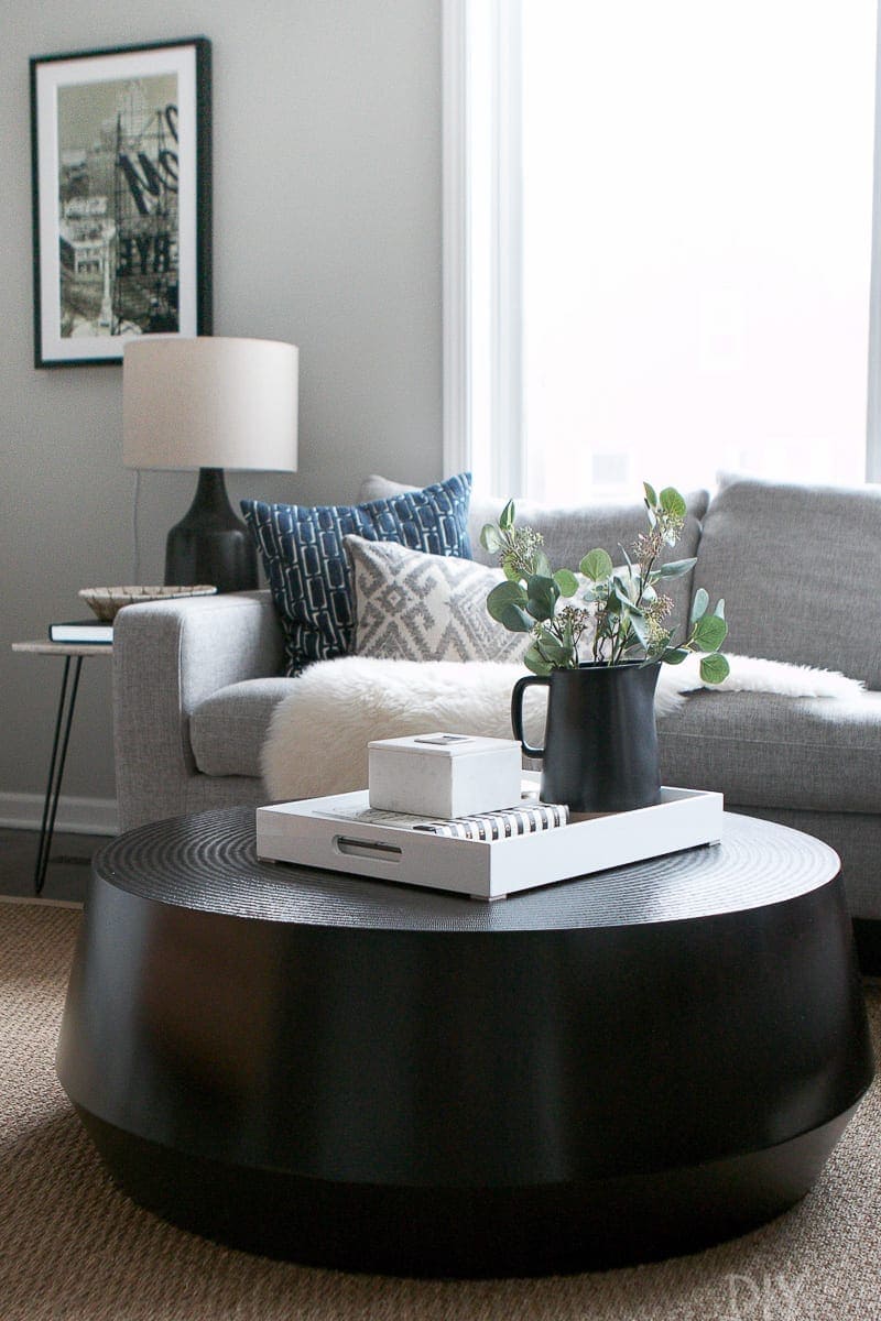 A black round coffee table complements the straight lines of a gray sectional in this family room. 