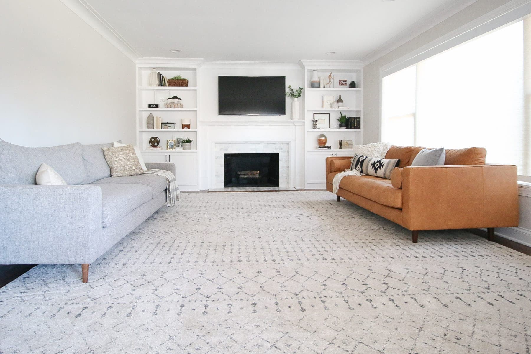 A large family room with a gray and brown leather couch.