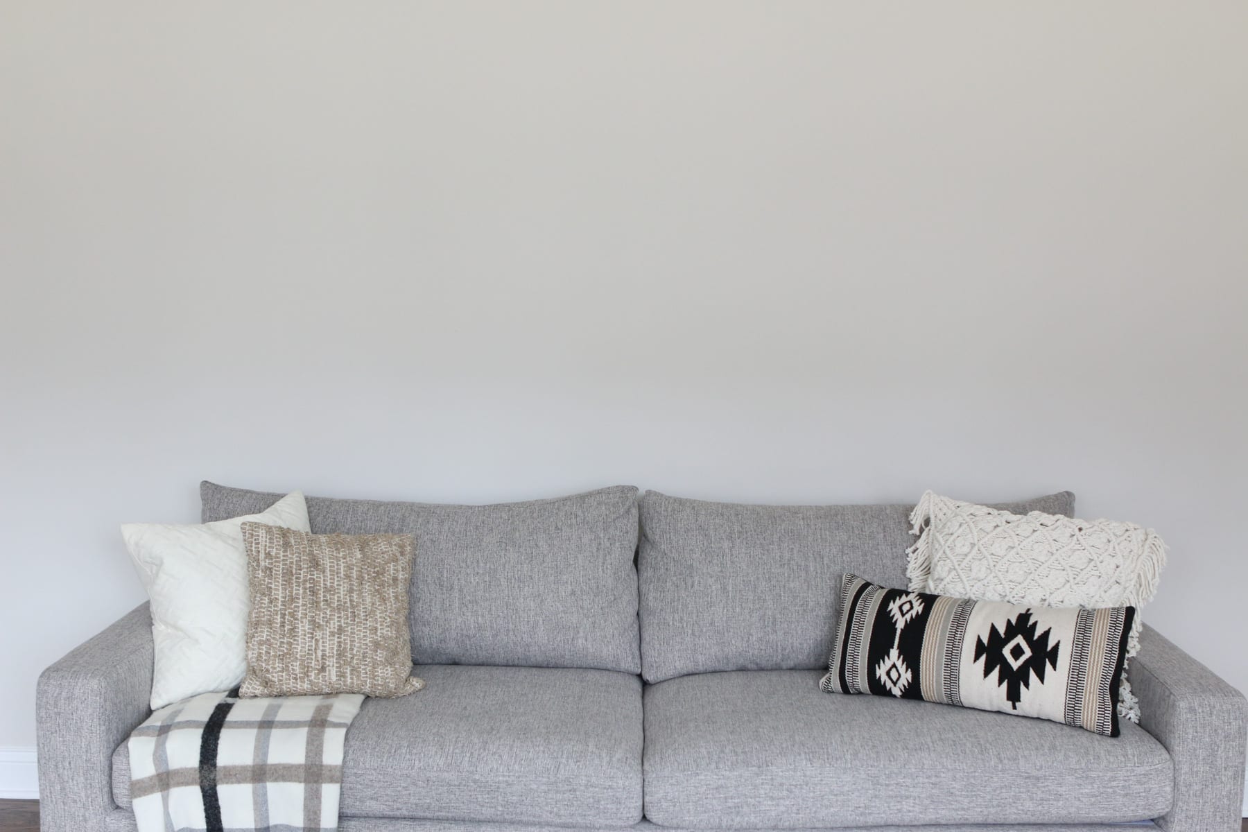 Blank wall over a gray couch in the family room.