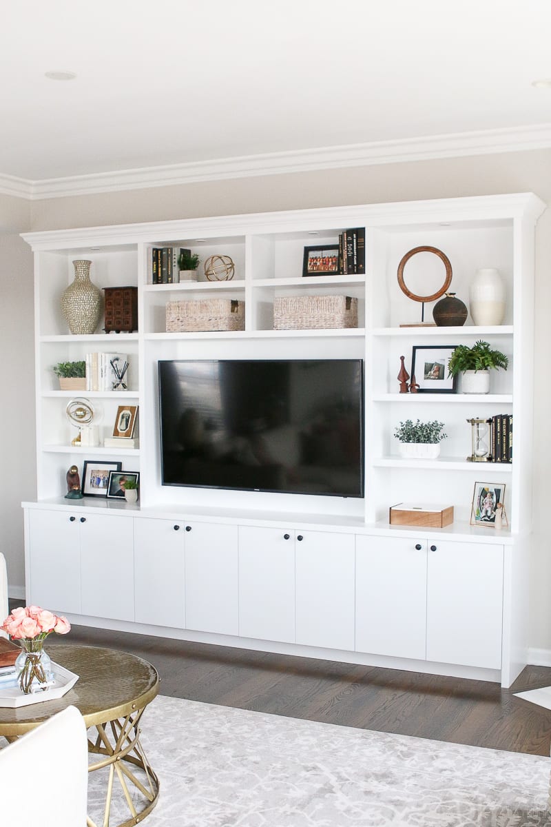 These white built-ins in this blush family room have lots of storage and room for accessories