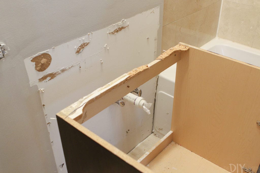 Unscrew the vanity from the wall and remove it from the bathroom