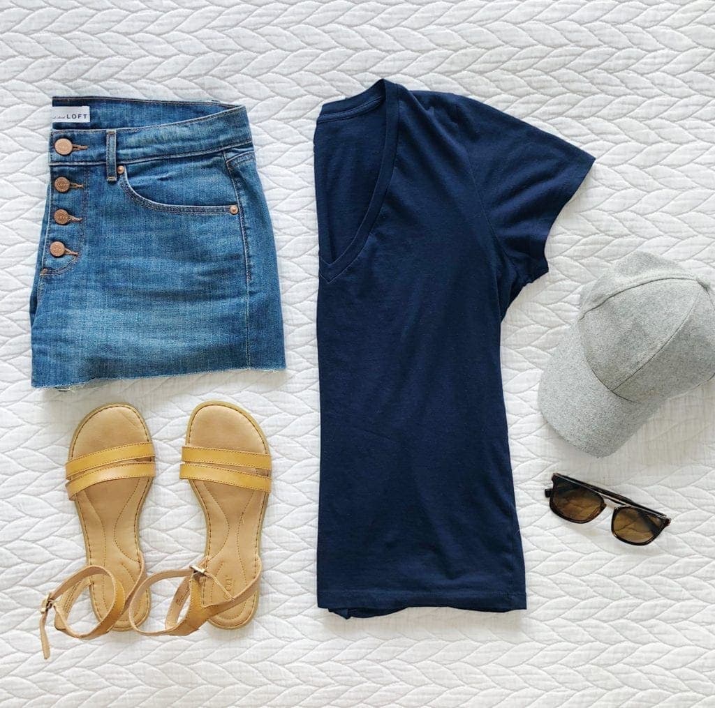A classic summer look with a navy t-shirt, jean shorts, and sandals