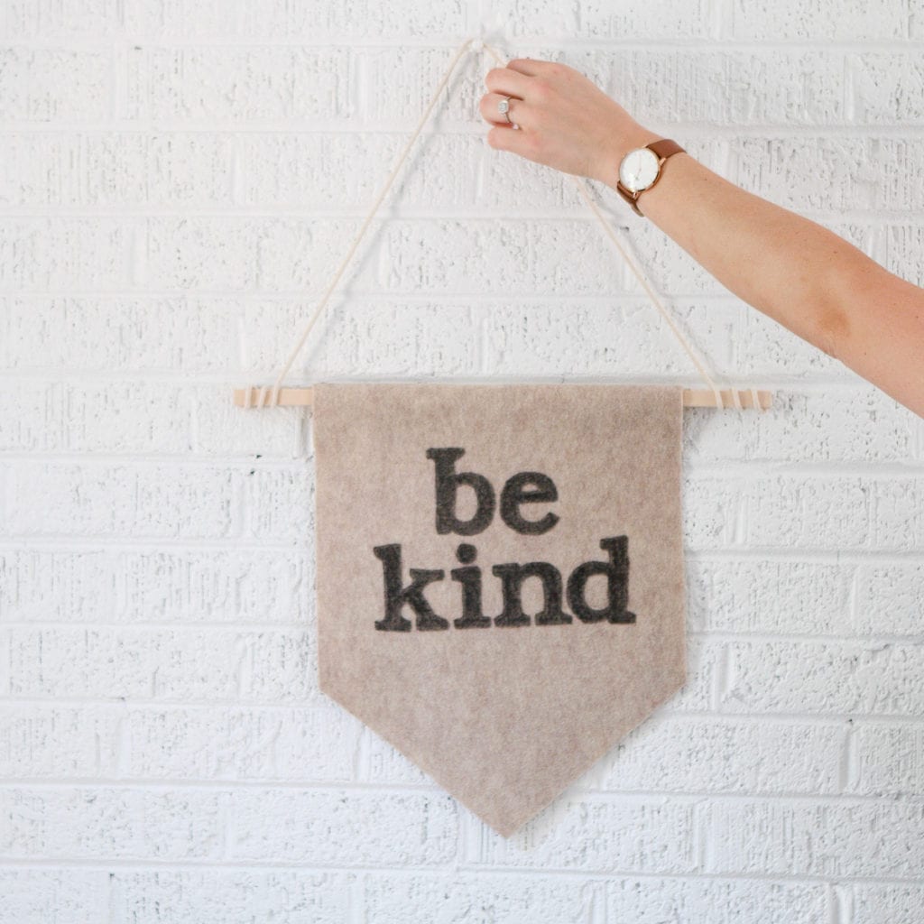 Hanging up a DIY wall pennant on a white brick wall