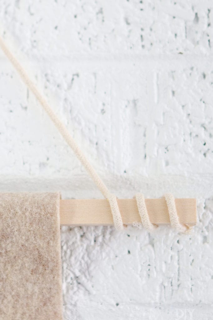Wrap the rope around the edges of the wood dowel when making the wall pennant