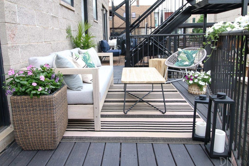 Create an outdoor room with a sofa, coffee table, and plants
