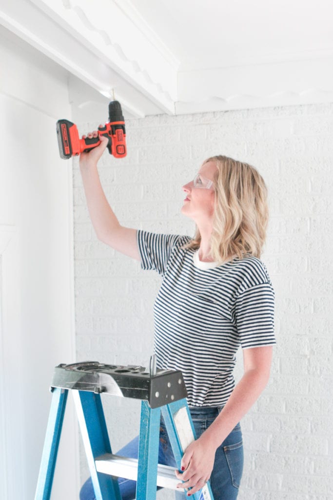 Drilling pilot holes into a wood beam to secure a hook for planters