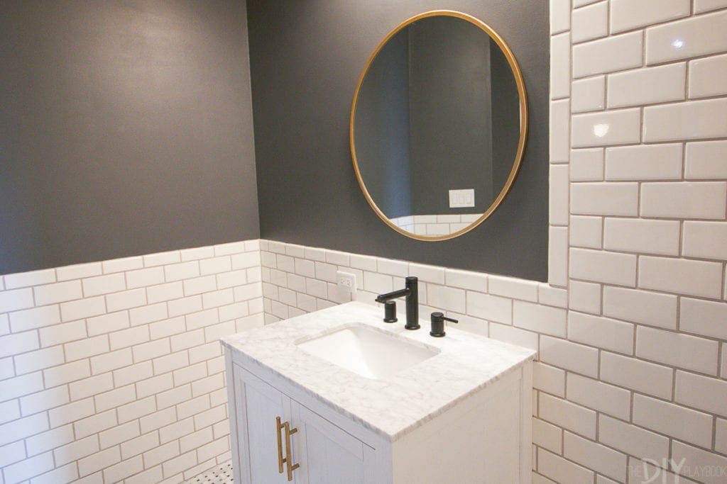 A gold mirror with a white vanity and dark gray paint
