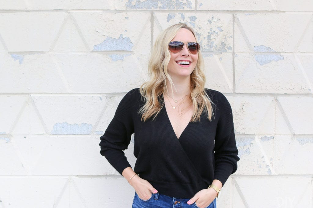 A casual black sweater with gold ray ban aviators