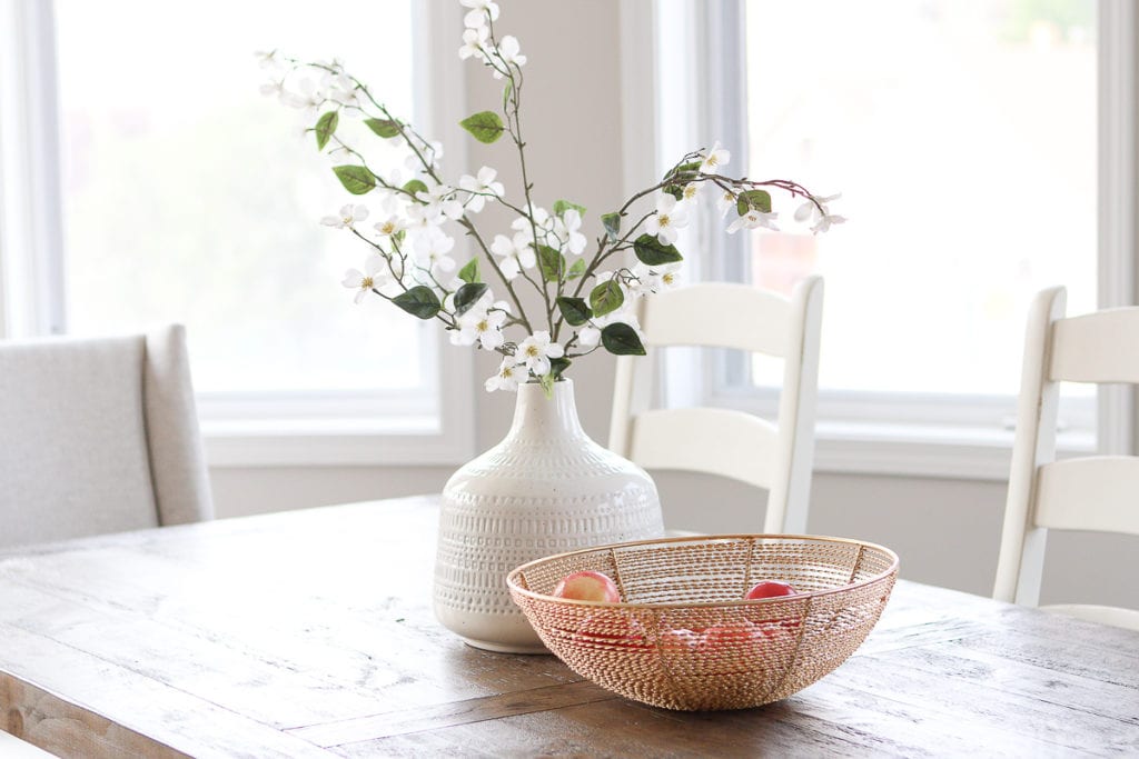 Adding branches to a white vase on a dining room table