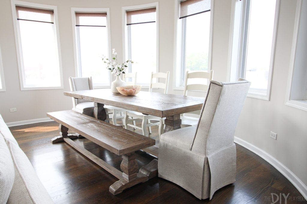 A farmhouse style wood table with wood chairs, a bench, and upholstered end chairs