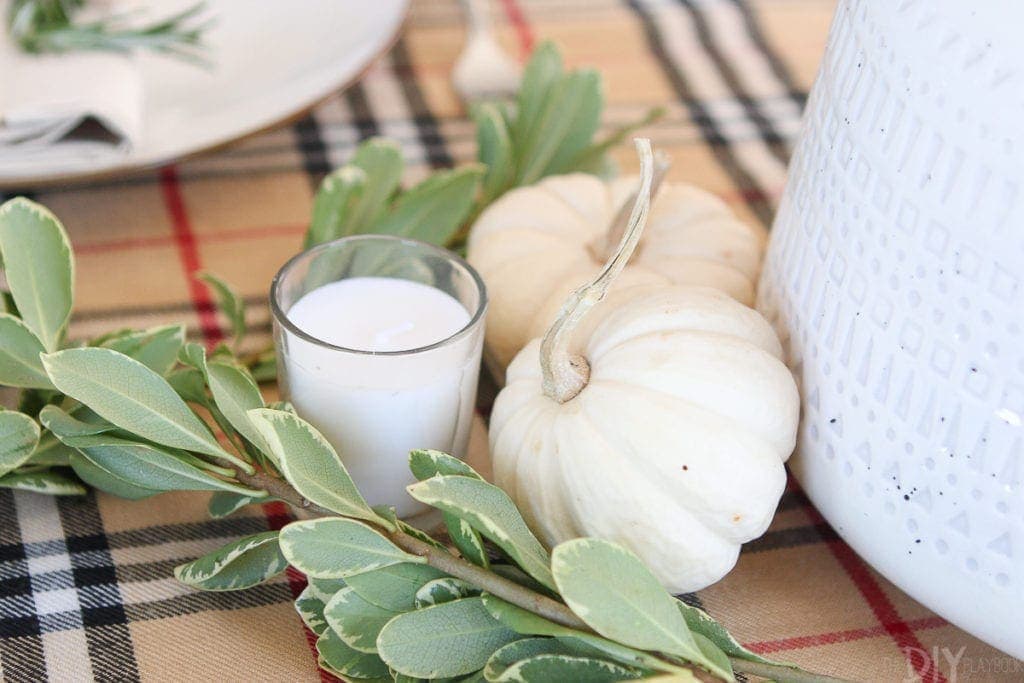 Candles, greenery, and white pumpkins work well on this tablescape