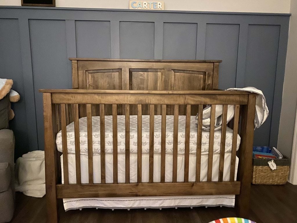 A blue wood wall treatment with a wood crib