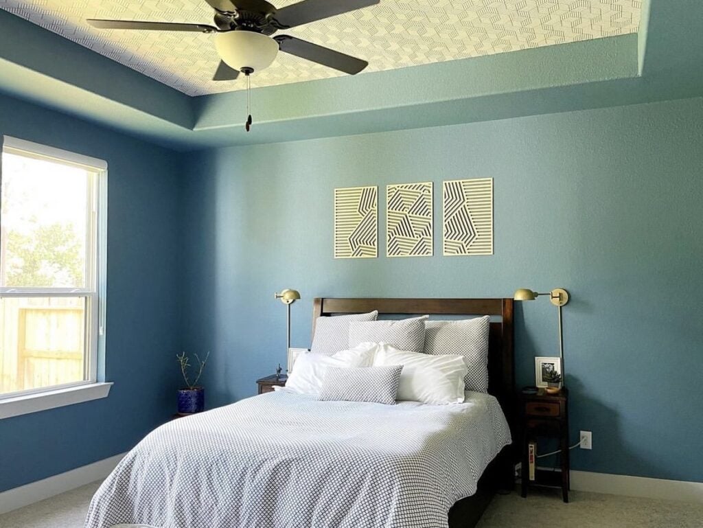 A blue bedroom with a wallpapered ceiling