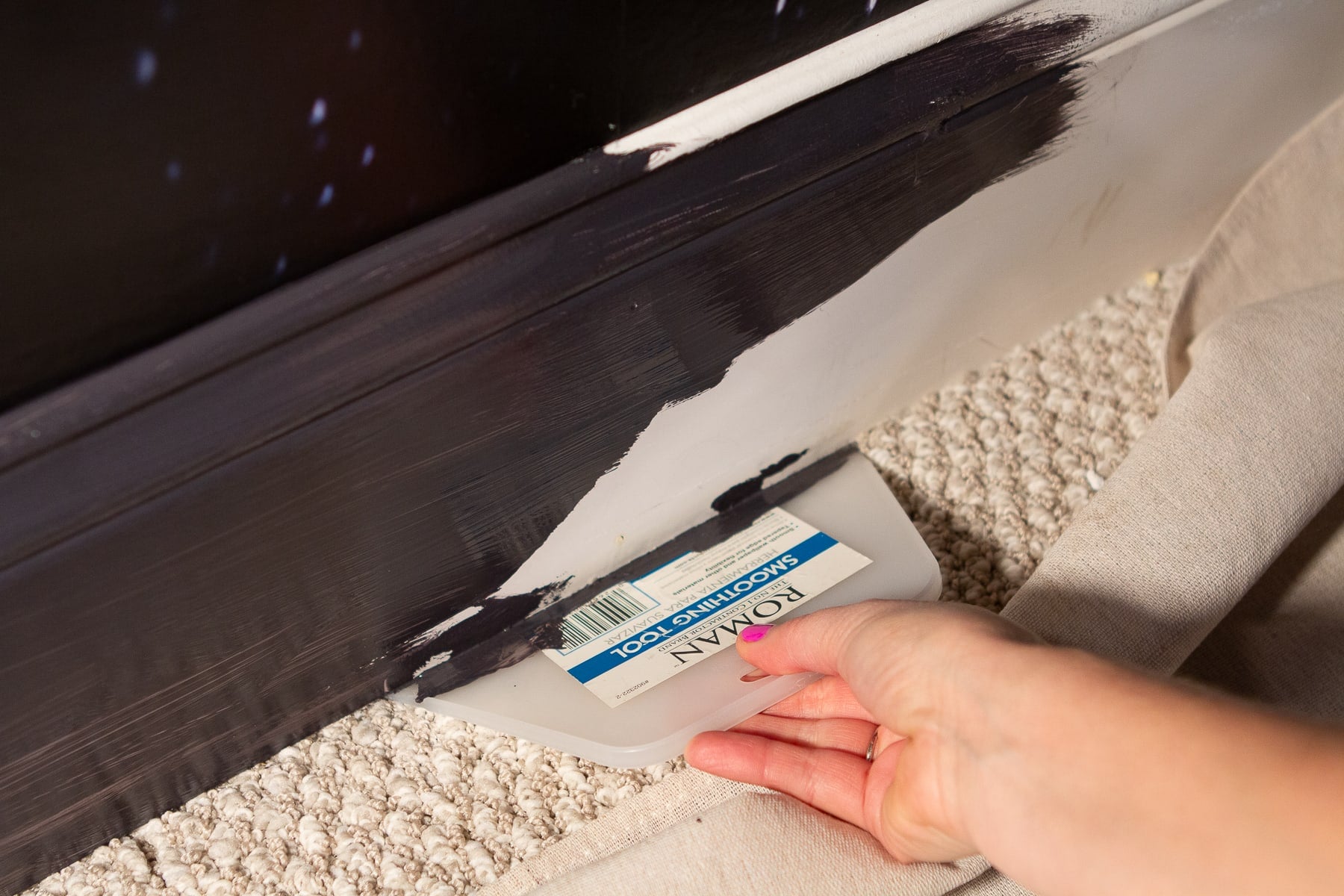 Sticking a flat wallpaper scraper underneath the baseboard before painting