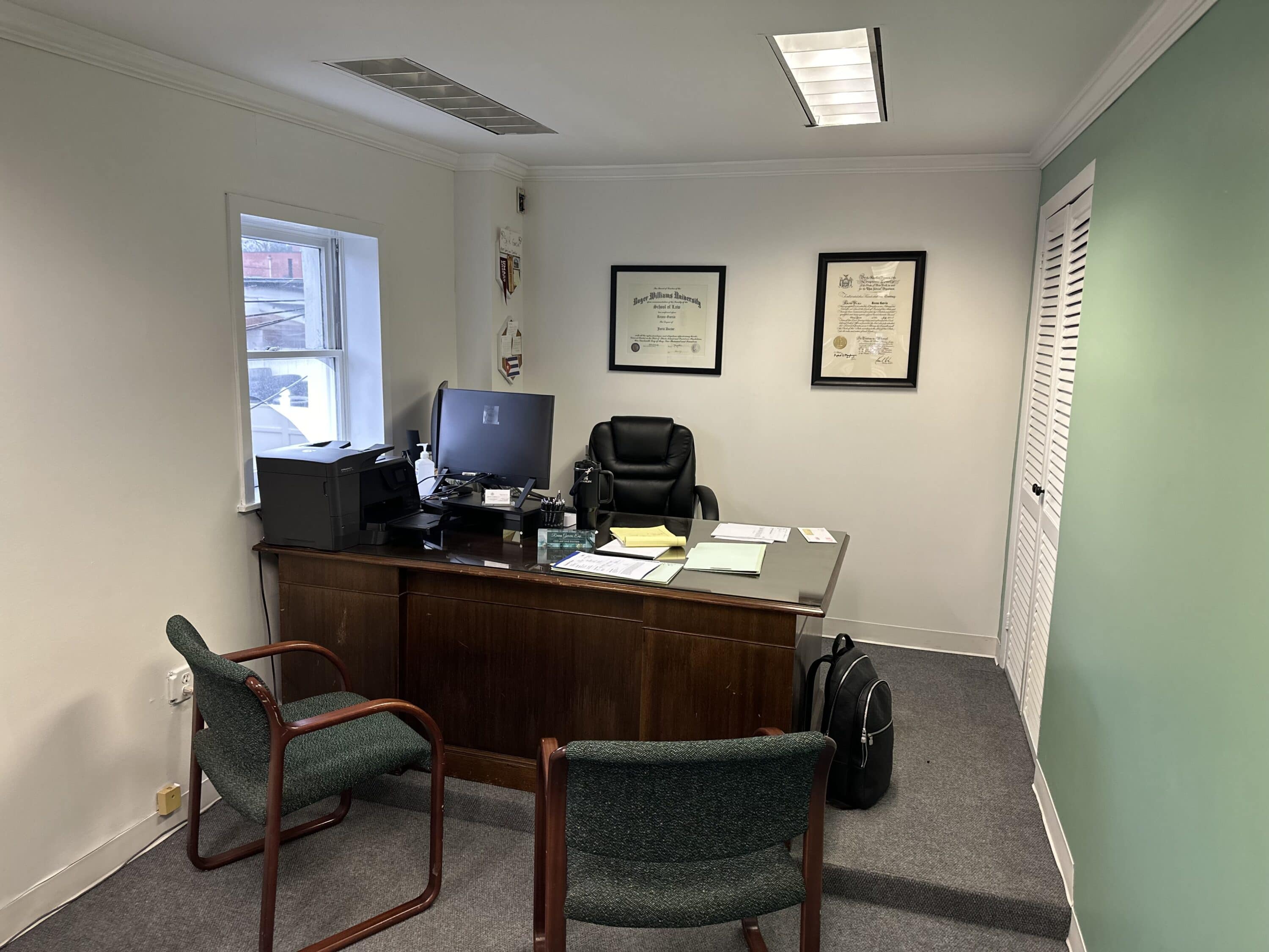 A law office with a large desk, computer, and mint green walls. 