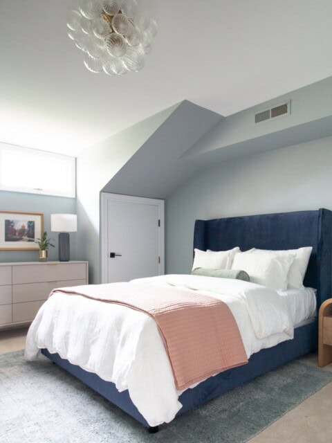 A grey and blue bedroom with a navy bed frame