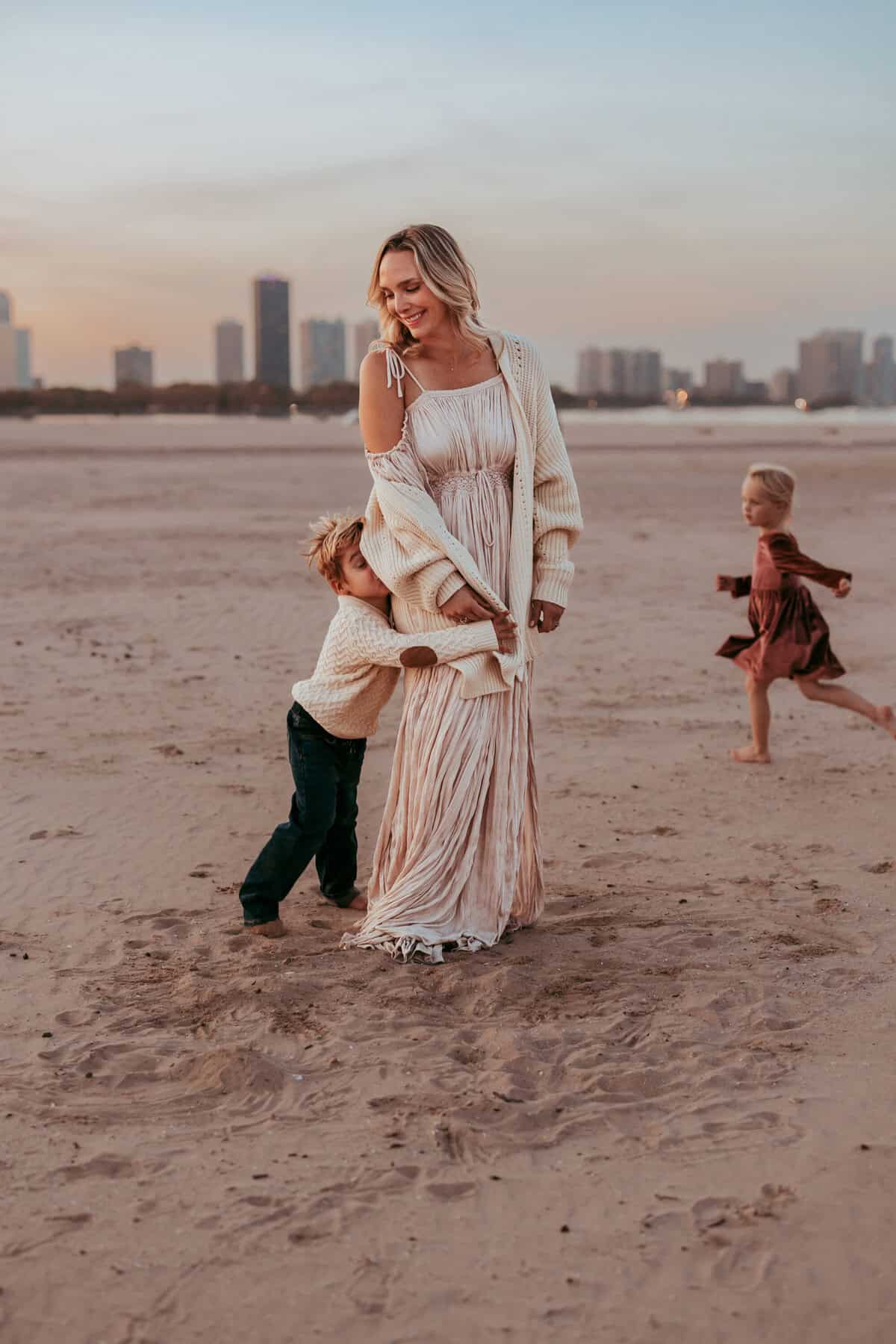 A mom with her children on the beach running in the sand