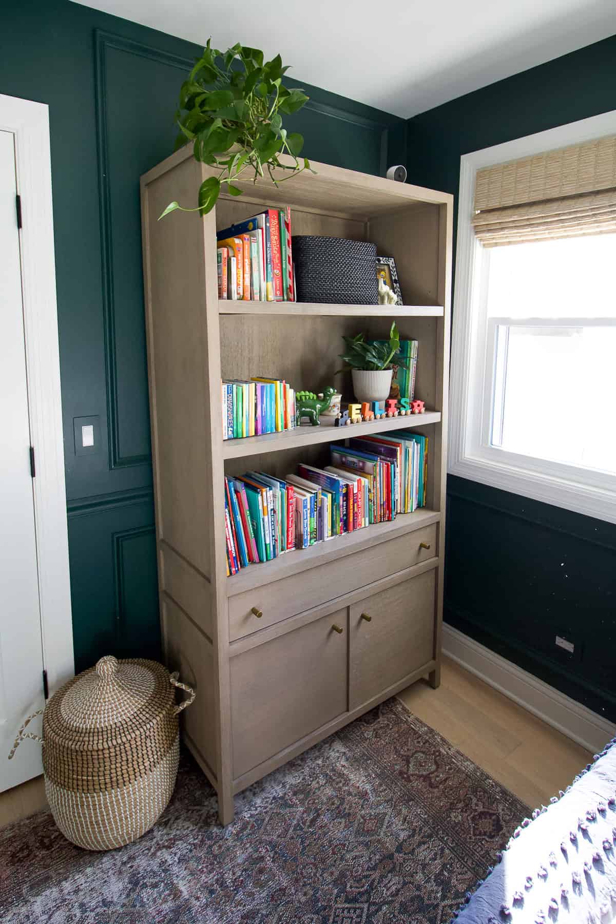 A wood bookshelf in a dark green bedroom