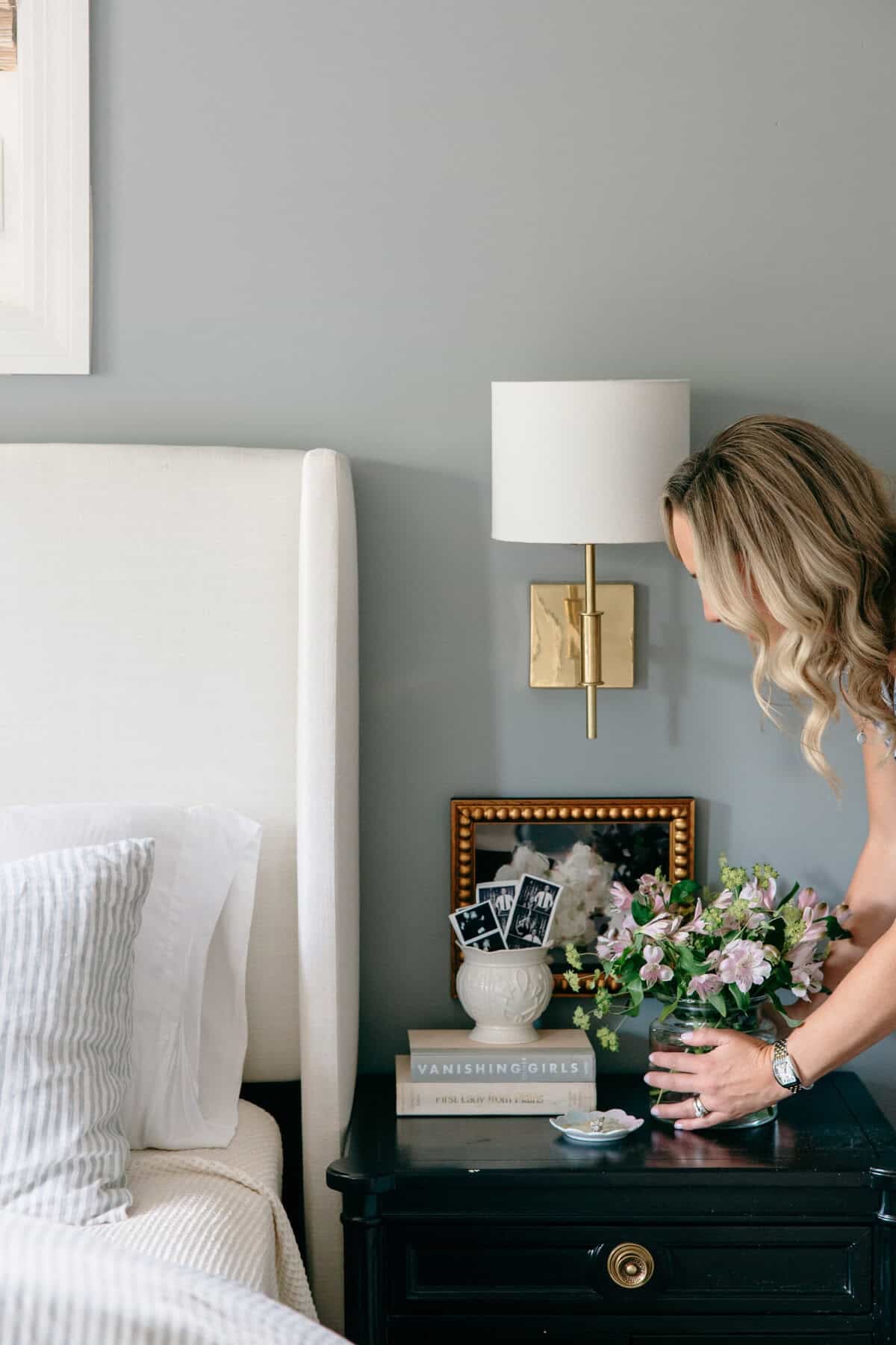 Fresh flowers in a vase on a bedroom nightstand, adding lived-in Nancy Meyers style to a cozy neutral space